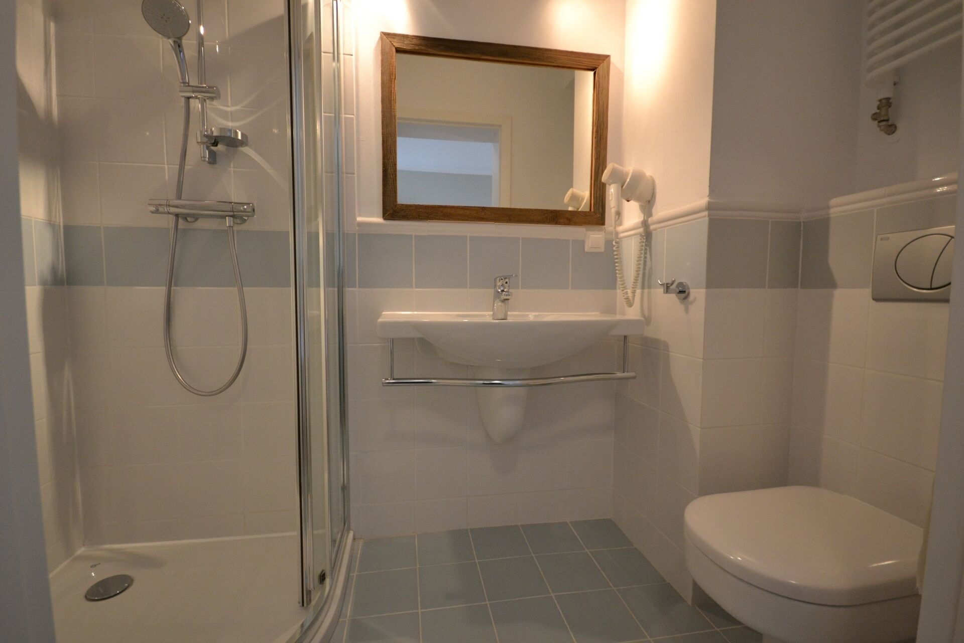 Ein Badezimmer mit einer Duschkabine, einem Waschbecken mit Spiegel darüber und einer Toilette.