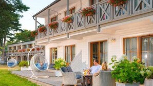 Un hotel con terraza, mobiliario de mimbre y plantas en macetas.