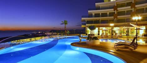 Una piscina cubierta, una piscina al aire libre, sombrillas, tumbonas