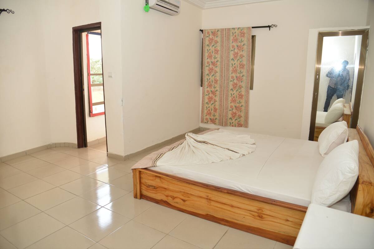A bedroom with a wooden bed, a window with curtains, and a door.