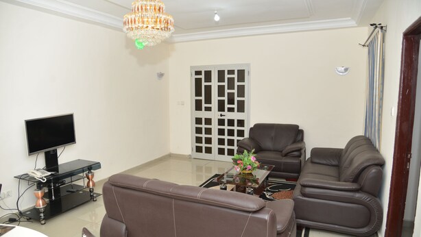 Una sala de estar con televisión, sofá y sillón.