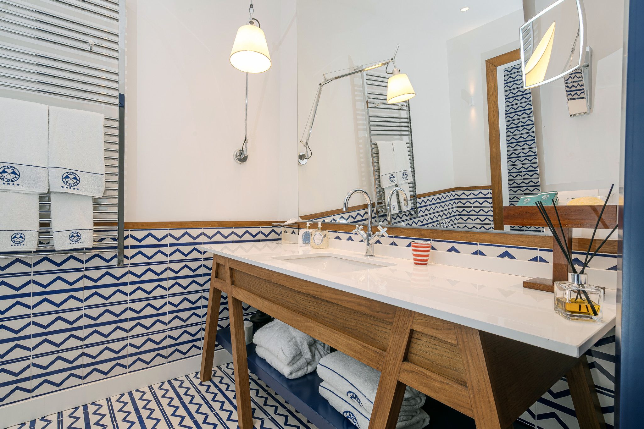 Une salle de bain avec un meuble-lavabo en bois, un miroir, un évier et des carreaux à motifs.