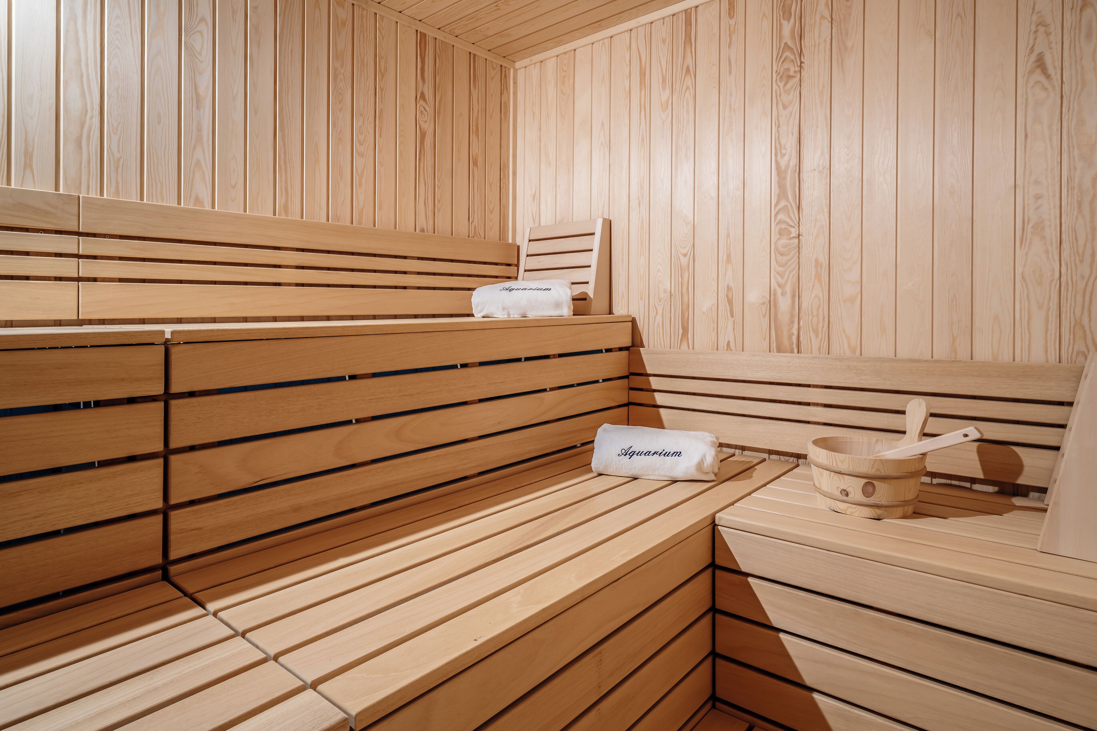 A wooden sauna with benches and a wooden bucket with a ladle.