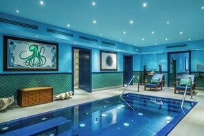 A modern indoor swimming pool with blue tiled walls and a large octopus mural. - Capo La Gala Hotel & Wellness (Vico Equense)