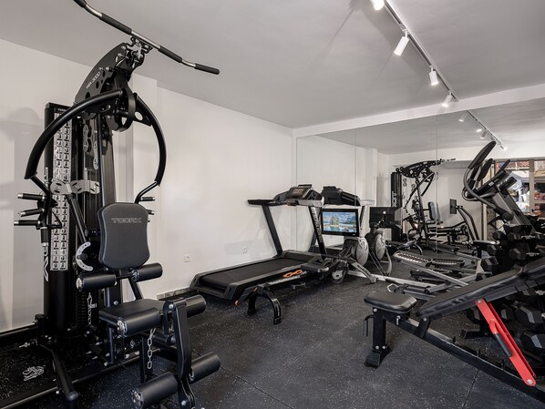 A gym with various exercise equipment, including a treadmill, weight machines, and a rowing machine. - Vergina Beach Resort (Chania)