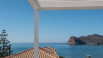A coastal view with a clear sky, a building with a tiled roof, and a lifeguard tower by the sea.