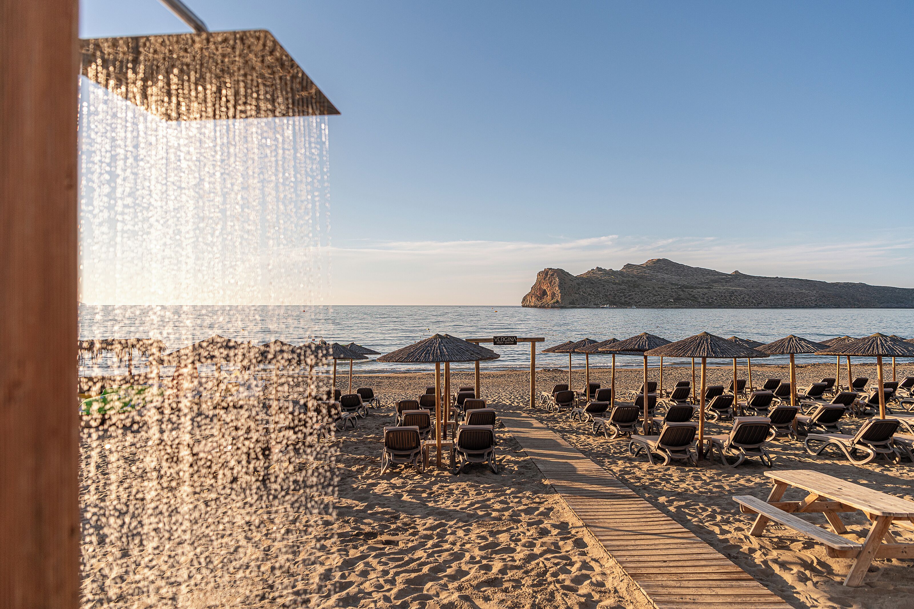 Une plage avec des chaises longues, des parasols et une promenade en bois.