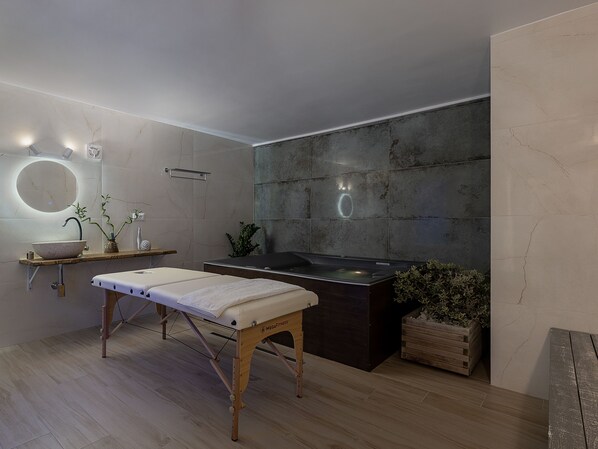 A modern bathroom with a wooden bench, a round mirror, a large sink, and a heated floor. - Vergina Beach Resort (Chania)