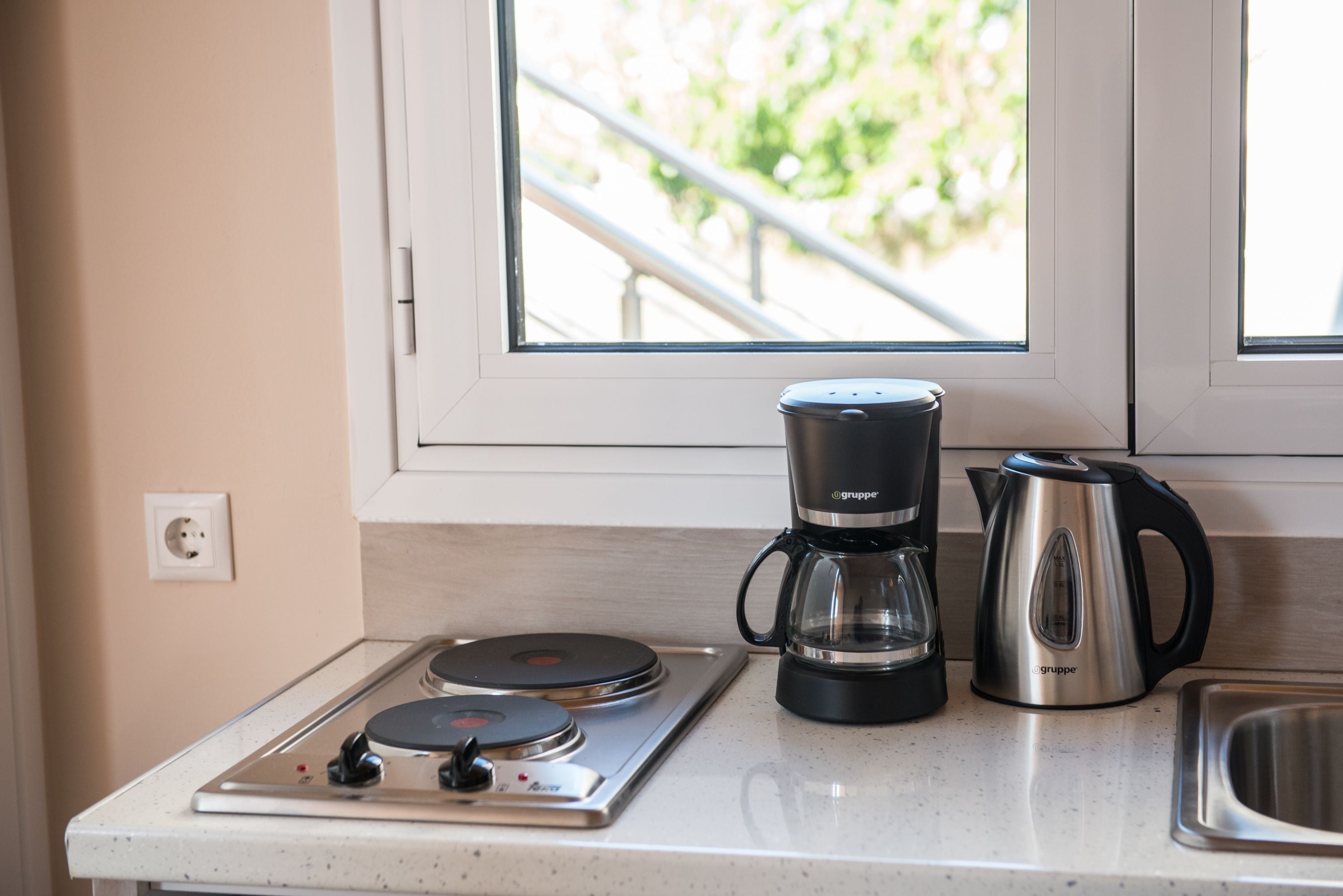 Uma cozinha com fogão a gás, cafeteira e chaleira em uma bancada.