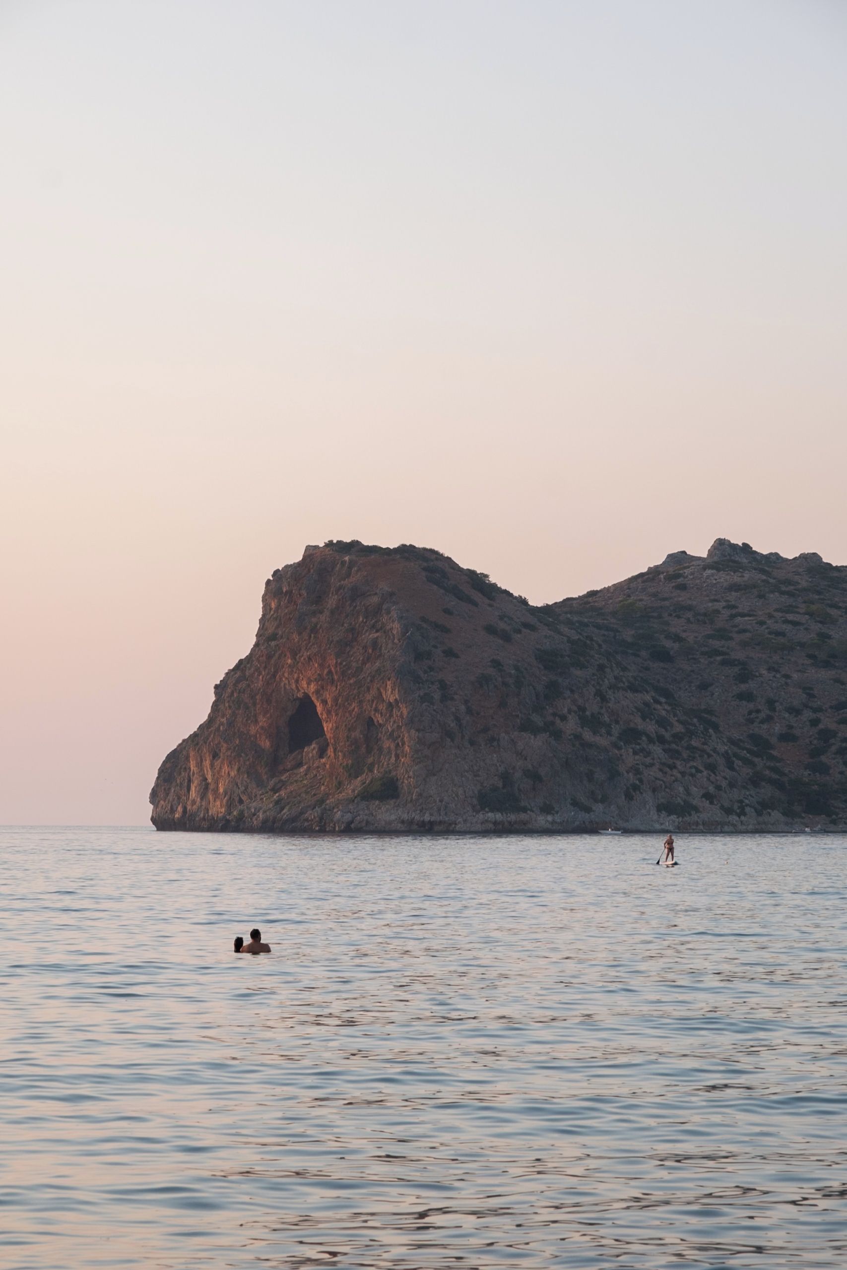 A coastal landscape with a prominent rock formation and calm waters.
