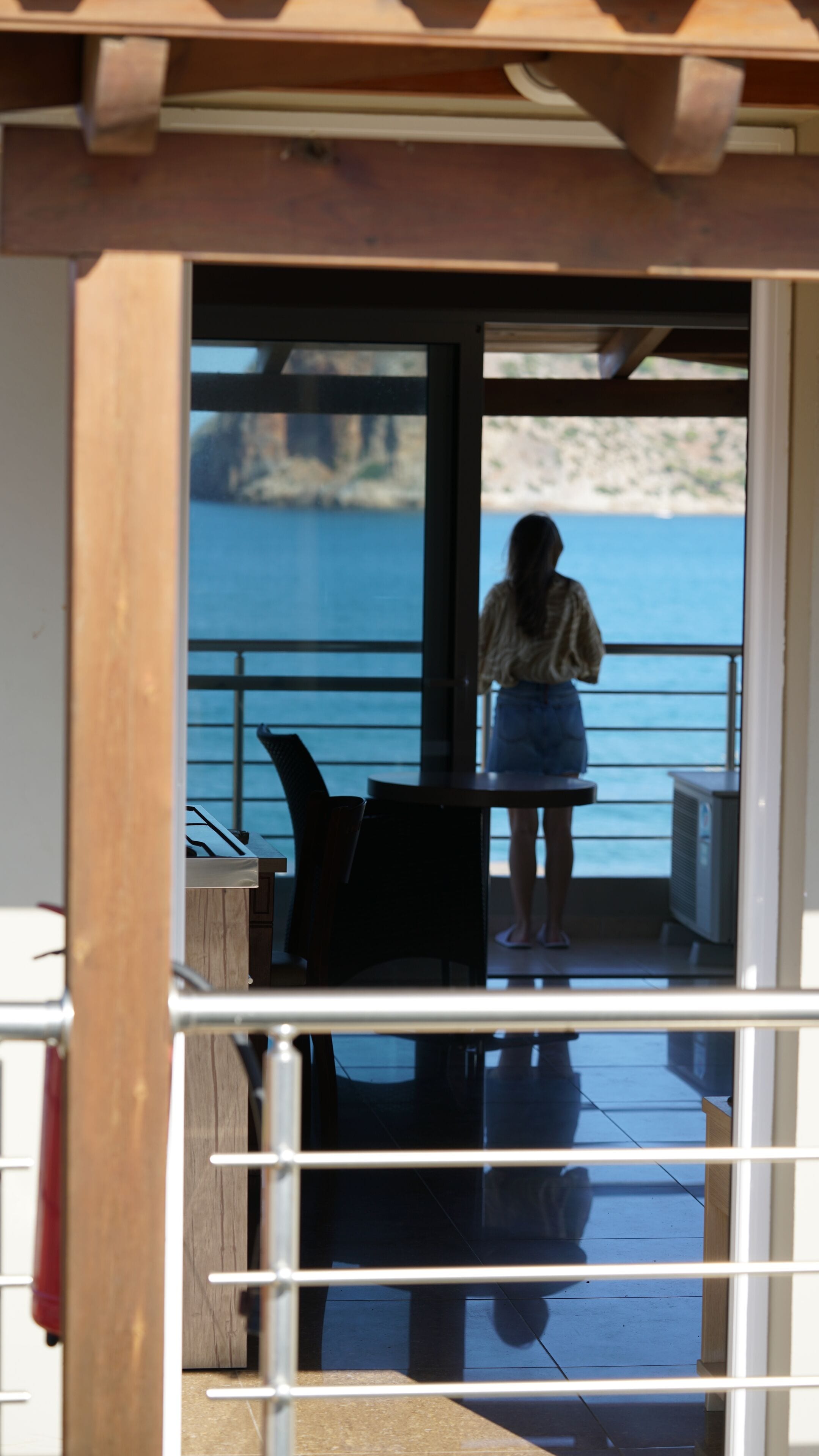 A person standing on a balcony with a view of the sea and cliffs.