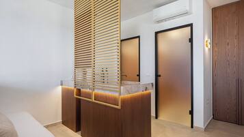 A modern bathroom with a wooden vanity, a marble countertop, and a frosted glass door.
