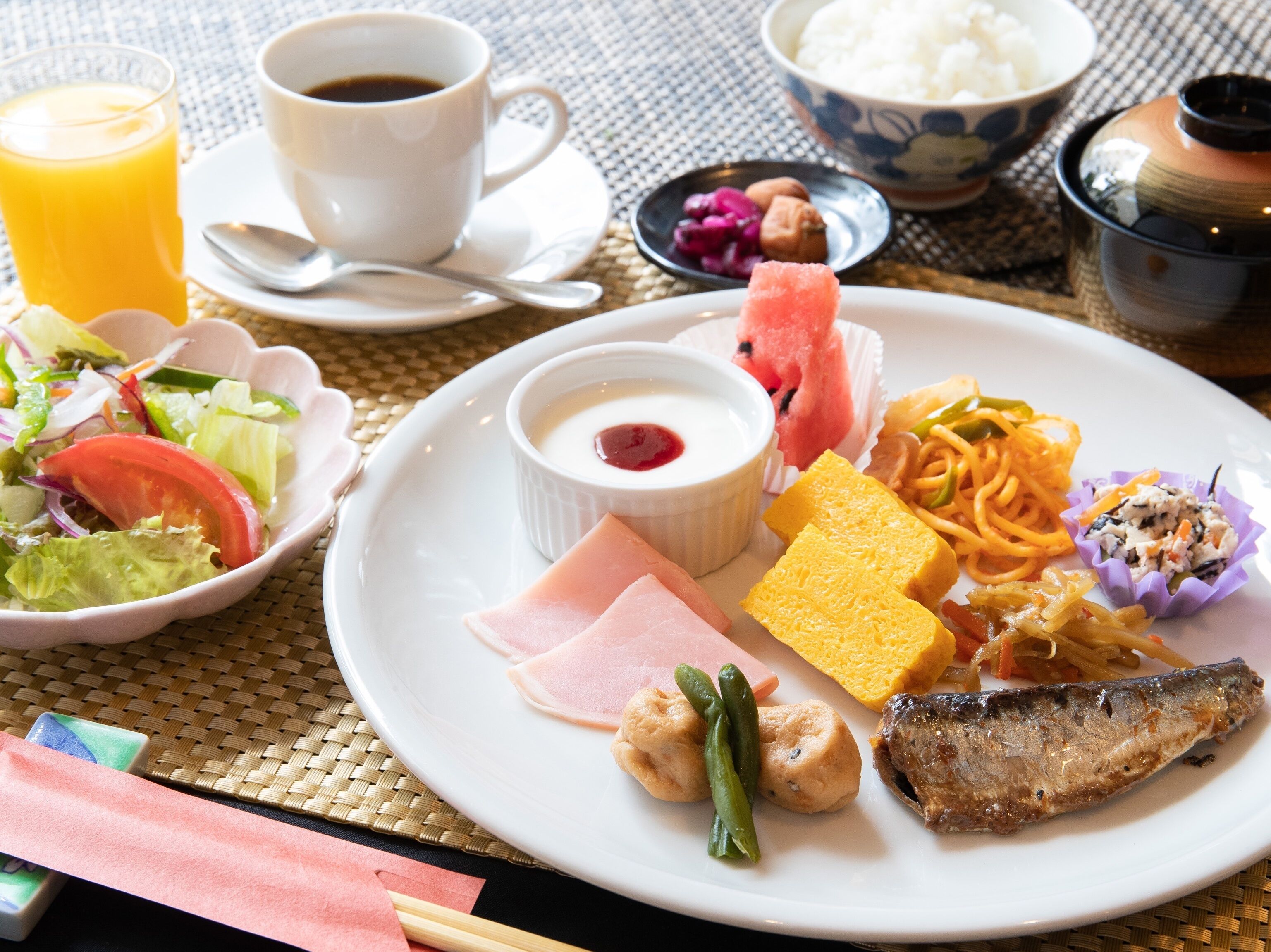 A meal with various dishes including a fish, vegetables, and a bowl of rice.
