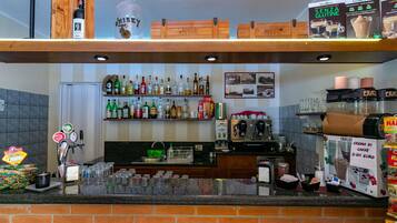 A bar area with a variety of liquor bottles, a coffee machine, and a display of food items.