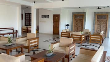 A spacious lobby with wooden furniture, a checkered floor, and a large door in the background.