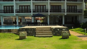 A hotel with a swimming pool, outdoor seating, and a stone staircase leading to the entrance. - Serendib Beach Resort (Induruwa)