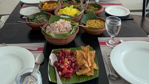 A dining table set with various dishes and drinks, surrounded by chairs and a view of a spacious room with a tiled floor and wooden furniture. - Serendib Beach Resort (Induruwa)