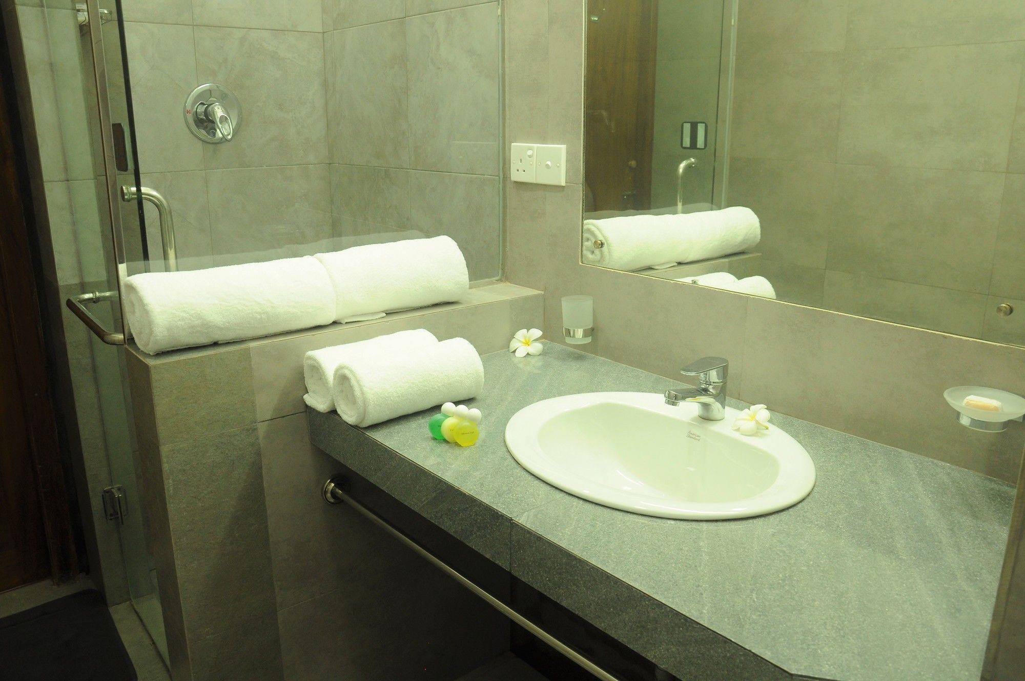 A modern bathroom with a glass shower enclosure, a sink with a mirror, and neatly arranged towels.
