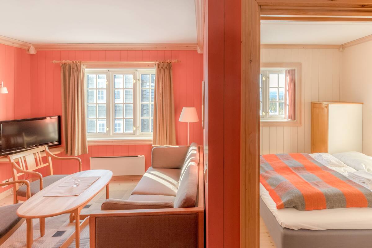 A room with a bed, a sofa, a table, and a TV.