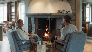 Una habitación con chimenea de piedra, dos sillones grises y una mesa de centro.