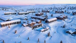 Un complejo turístico cubierto de nieve con varias cabañas, una piscina y un paisaje nevado.