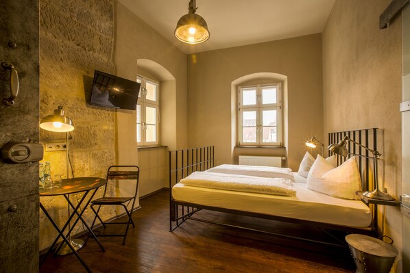 Un dormitorio con cama, escritorio, silla, televisor y ventana.