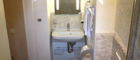 Une petite salle de bain comprenant des toilettes, un lavabo et une douche.