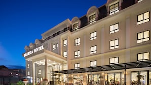 A hotel with a covered outdoor seating area, multiple floors, and a well-lit entrance. - Freesia Hotel (Sa Pa)