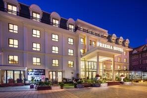 A hotel with a large entrance, a sign for a foot and body massage service, and a well-lit outdoor area with plants and seating. - Freesia Hotel (Sa Pa)
