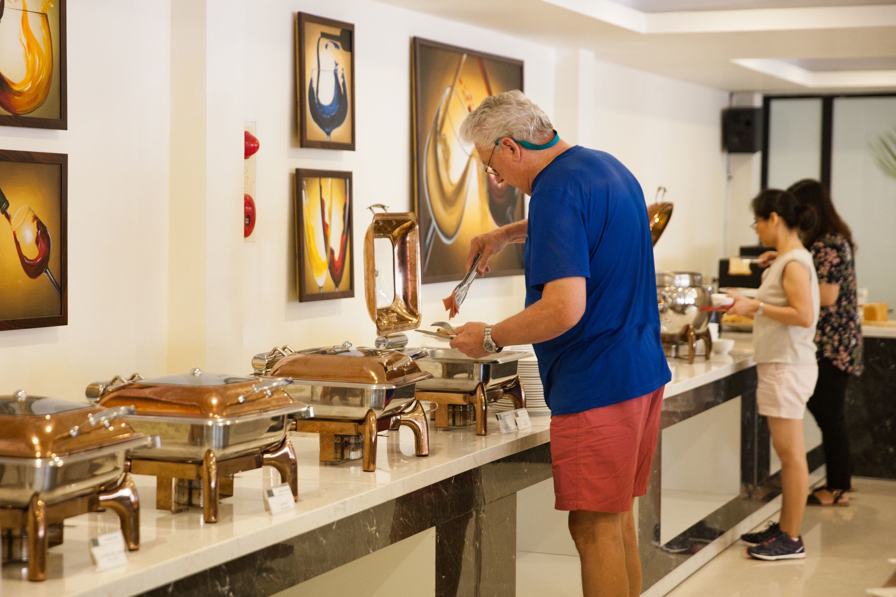 A buffet setup with various food containers and a person serving food.