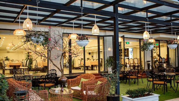 An outdoor seating area with wicker furniture, hanging pendant lights, and potted plants. - Freesia Hotel (Sa Pa)