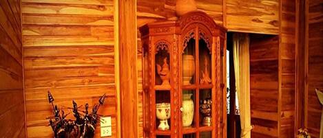 A wooden interior with a cabinet displaying pottery and a small statue.