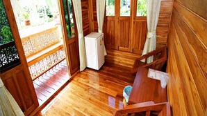 Interior de una cabaña de madera con una escalera de madera, un refrigerador blanco pequeño y un banco de madera.