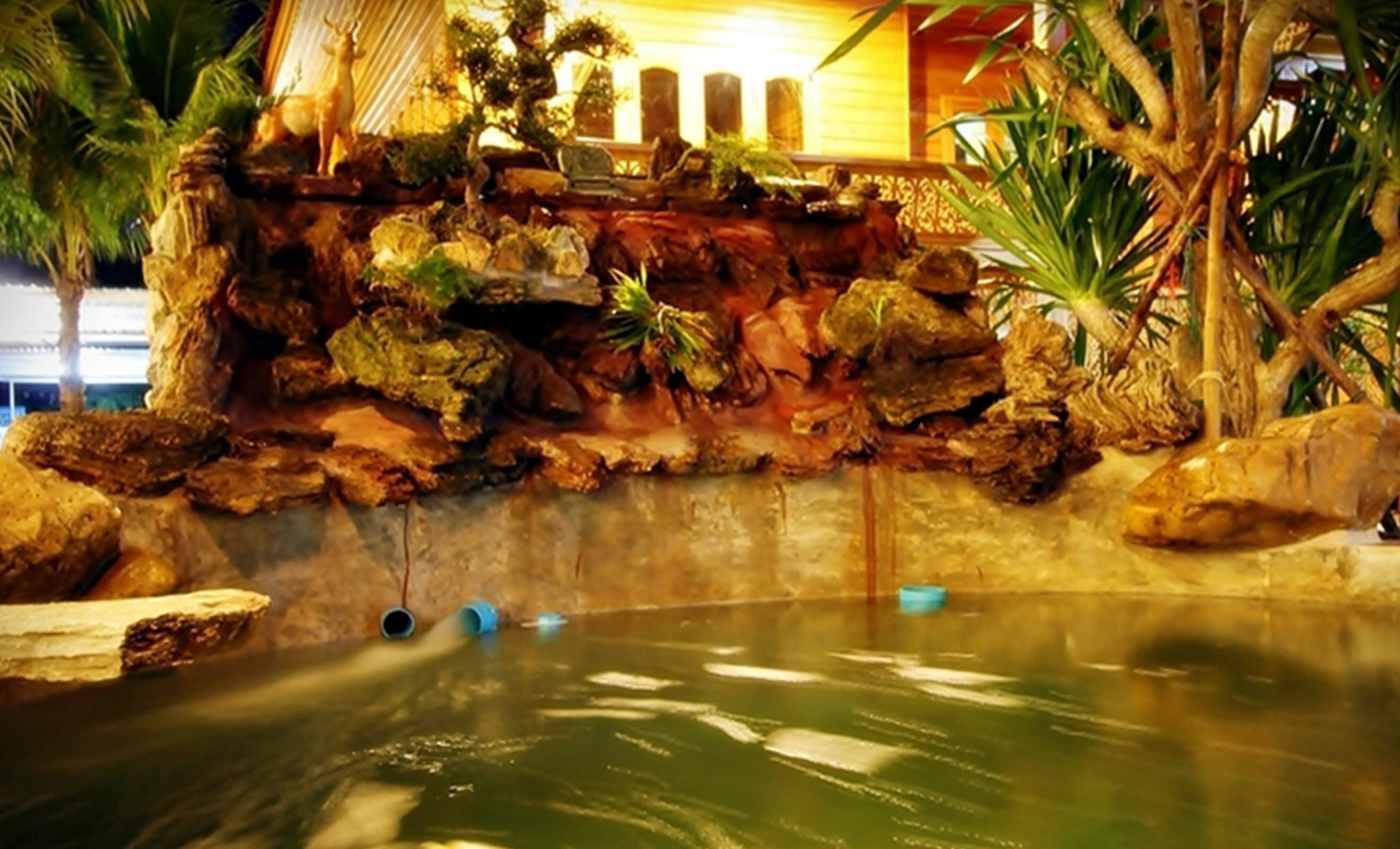 A water feature with rocks and plants, a small pool, and a decorative deer statue.