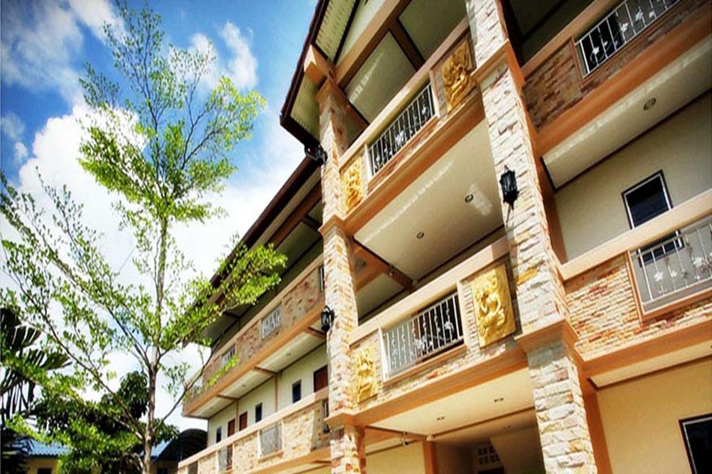 A multi-story hotel with balconies, stone facade, and a clear sky.
