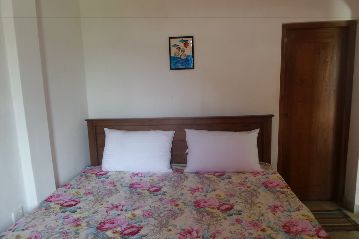 A bed with a floral bedspread, a wooden headboard, and a small framed picture on the wall.