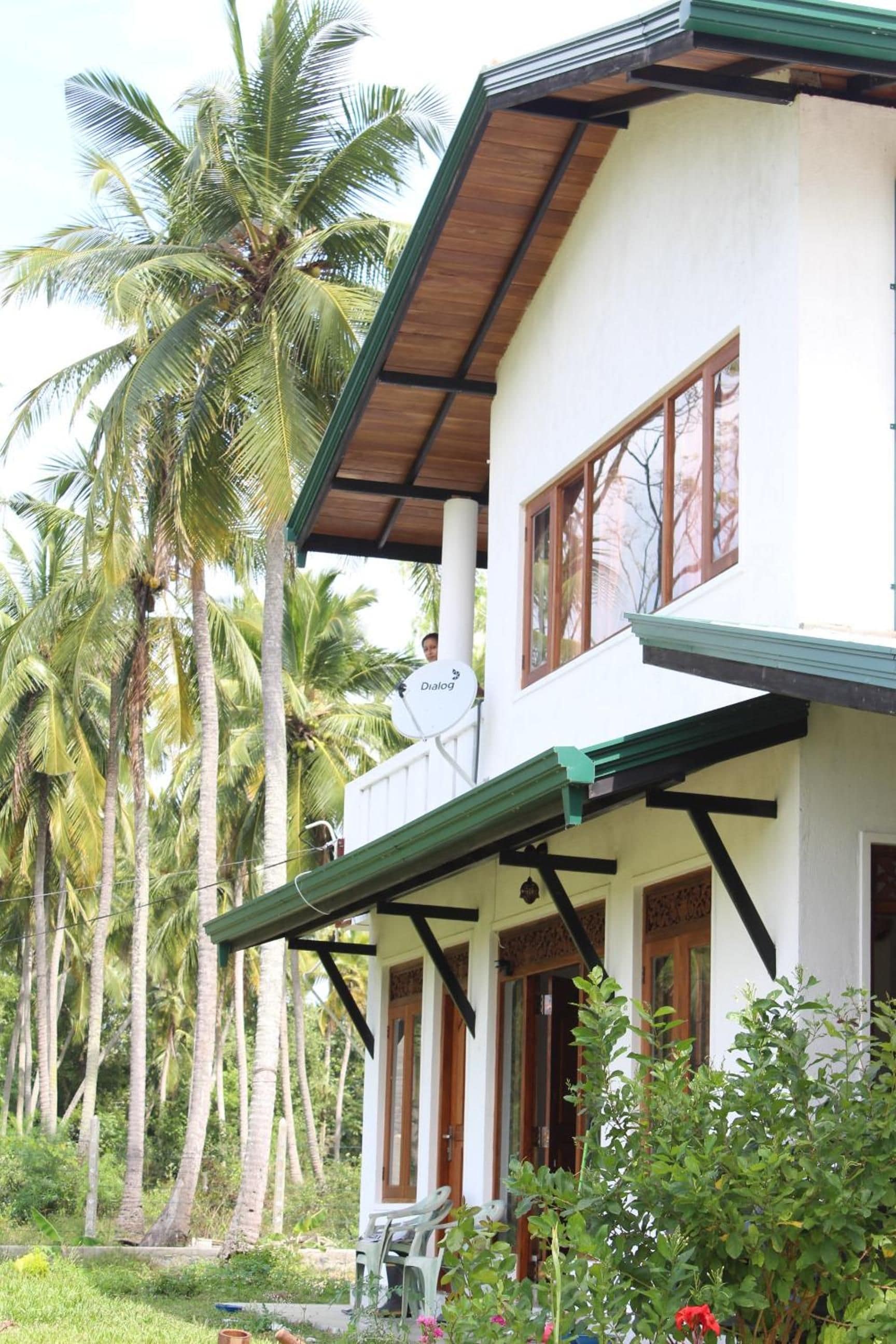 A two-story building with a balcony, surrounded by palm trees.