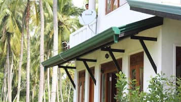 A two-story building with a balcony, surrounded by palm trees.