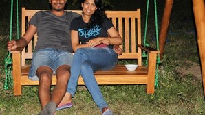 A wooden swing set with two people seated on it. - CoCoWorld Bungalow (Panduwasnuwara)