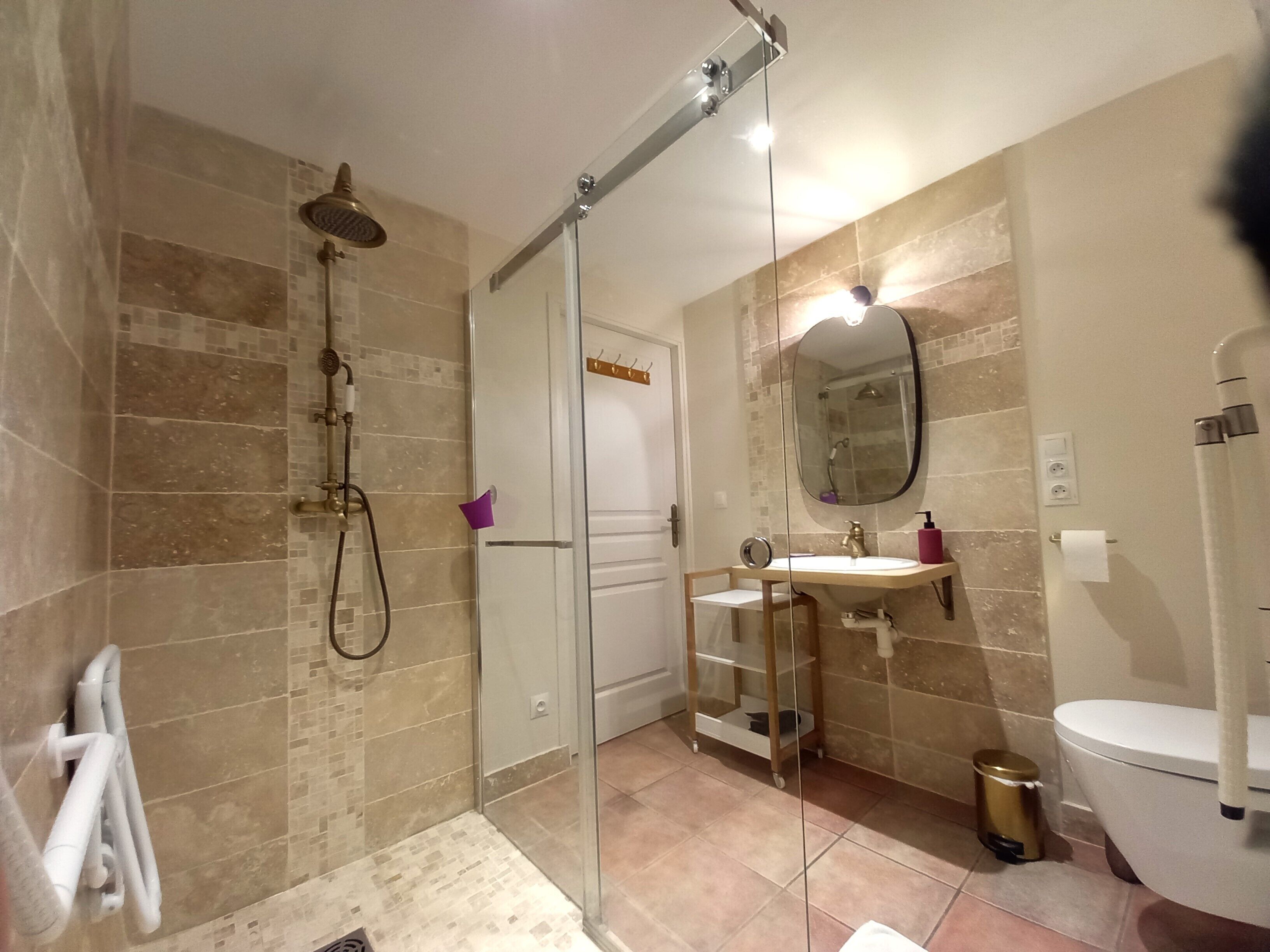 Un baño moderno con cabina de ducha de vidrio, un lavabo blanco con mueble y un inodoro.