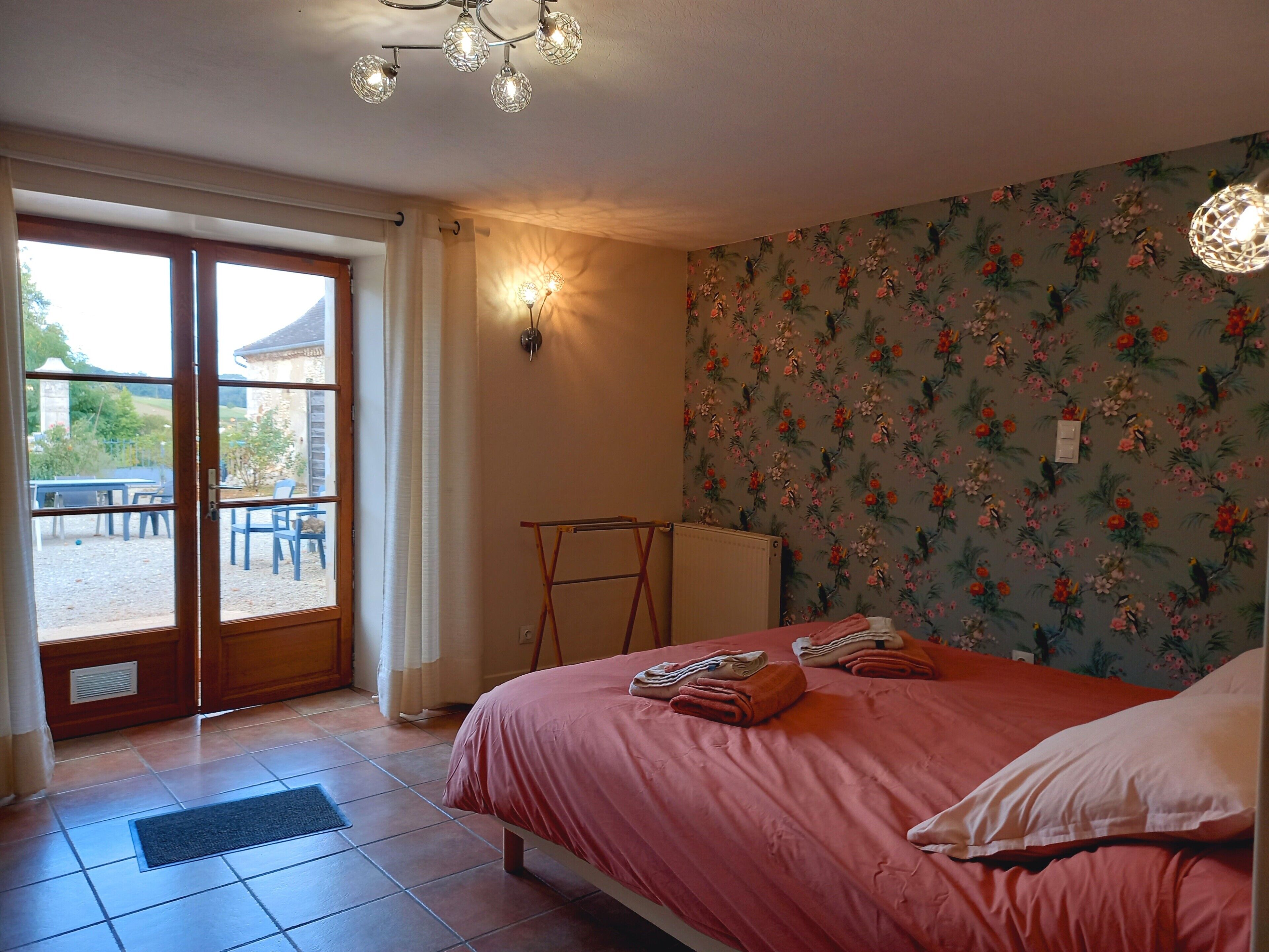 A bedroom with a bed, a radiator, a window, and a door leading to an outdoor area.