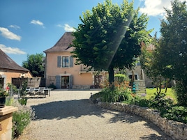 A two-story house with a gravel driveway, a wooden fence, and a garden with various plants and flowers.