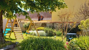 Un jardín con una escalera de madera, un muro de piedra y una pequeña mesa con sillas.
