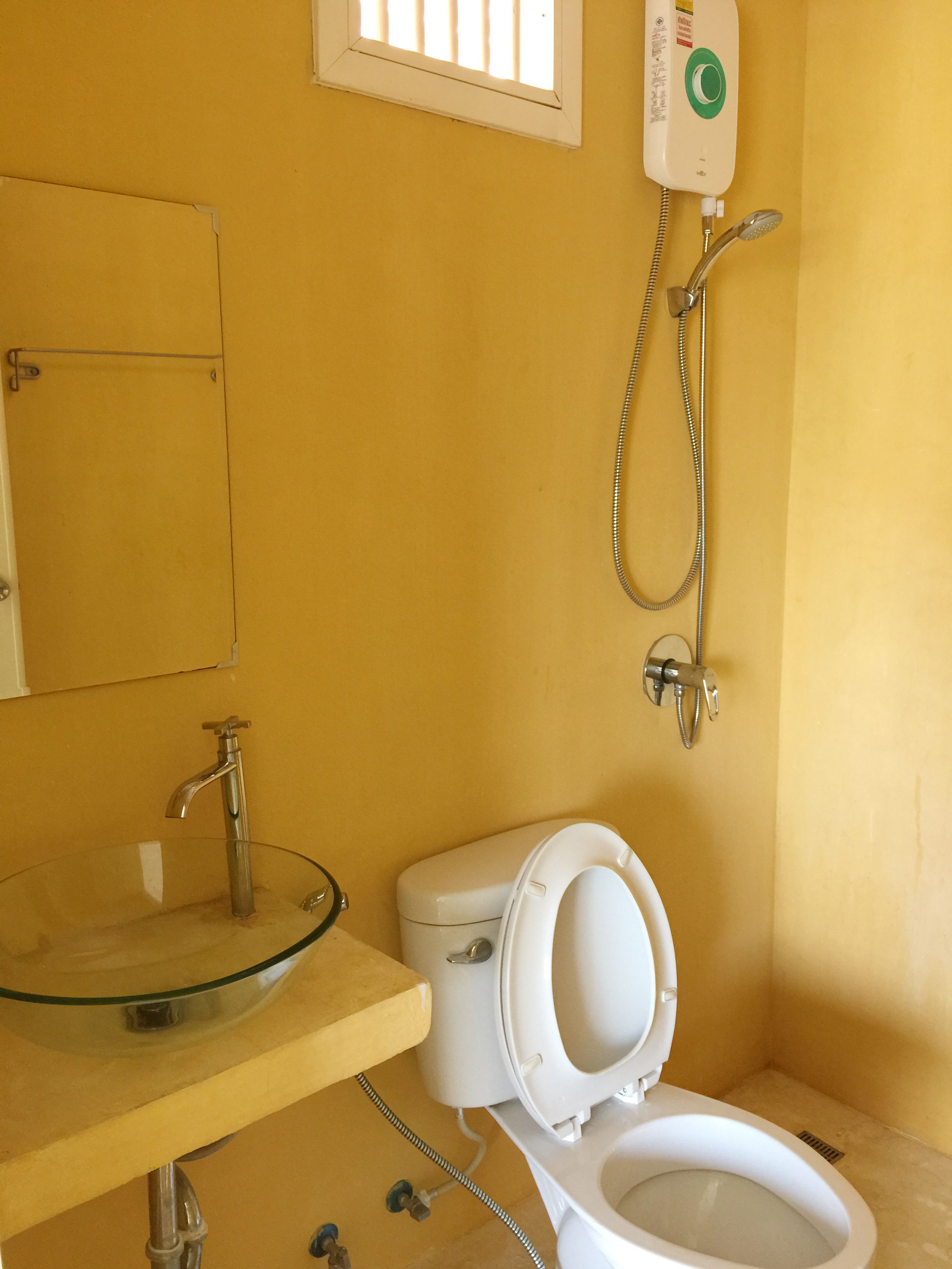 A bathroom with a glass sink, a toilet, and a shower.
