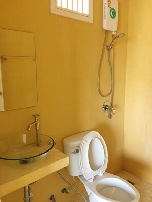 Un baño con un lavabo de cristal, un inodoro y una ducha.