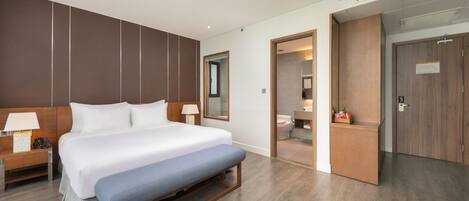 Ein modernes Hotelzimmer mit einem großen Bett, Nachttischen, einer Bank und einem Holzschrank.