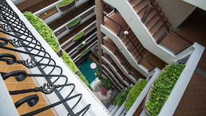 A multi-level atrium with a central pool, balconies with planters, and a staircase. - Sa-Bai-Dee Condo (Chonburi)