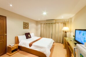 A hotel room with a bed, bedside table, lamp, TV, and curtains. - Sa-Bai-Dee Condo (Chonburi)