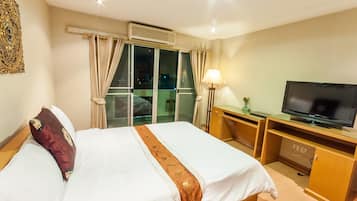 Ein Hotelzimmer mit Bett, Fernseher, Schreibtisch und einem Fenster mit Vorhängen.