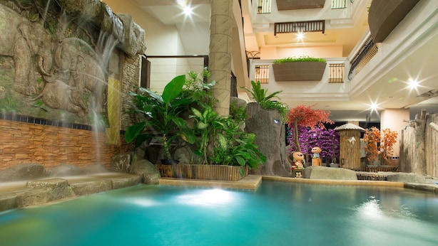 A serene indoor pool area with a waterfall feature, surrounded by lush greenery and decorative elements. - Sa-Bai-Dee Condo (Chonburi)